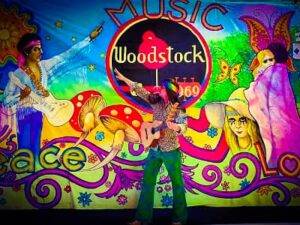 Woodstock feestavond Themafeest organiseren?  Compleet Hippie Flower Power feestpakket inclusief zanger, gitarist, dj, decoratie  Avondvullend feestprogramma 
