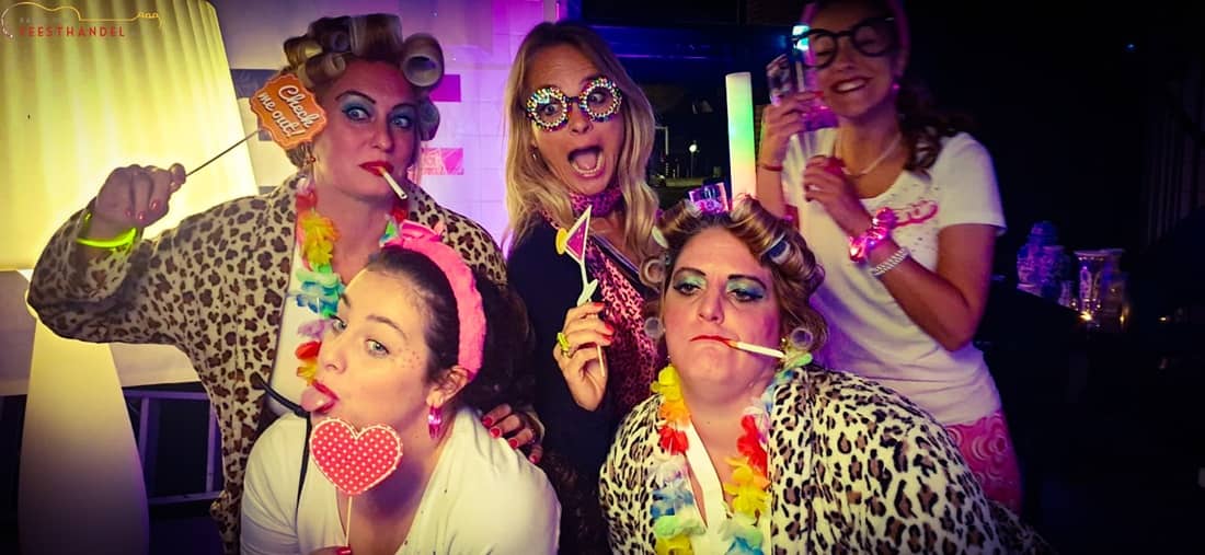 Groep feestende mensen tijdens een foute hits bingo met kleurrijke verlichting, bingokaarten en uitbundige sfeer