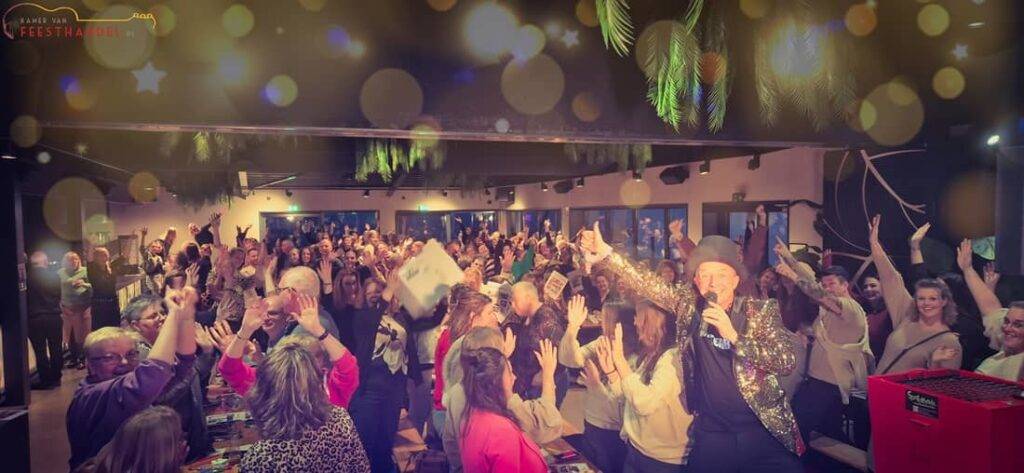 Ik Hou van Holland 3 - 1100x580 - Kamer van Feesthandel Een grote groep enthousiaste mensen juicht en lacht tijdens de ‘Ik Hou van Holland’ spel- en quizshow van Kamer van Feesthandel, in een feestelijke Hollandse sfeer vol entertainment en teamspirit